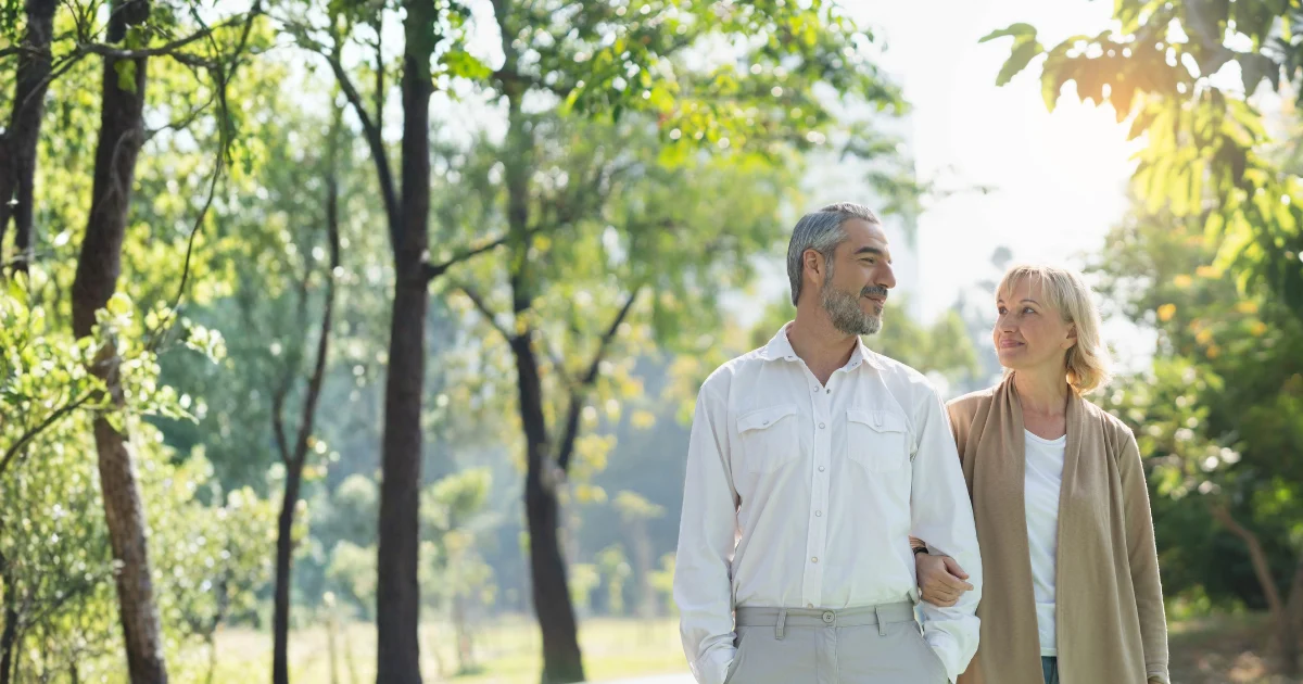 milli-blog-general-provider-patient-tablet-01 An older couple walks arm in arm outdoors in warm natural light