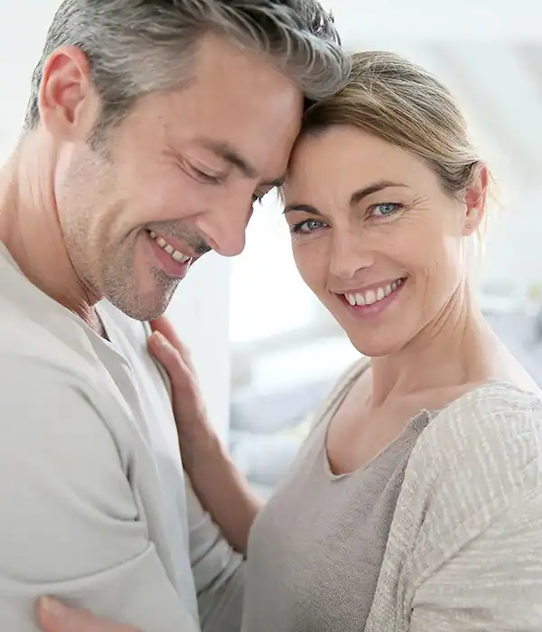 Couple smiling and embracing, looking at camera