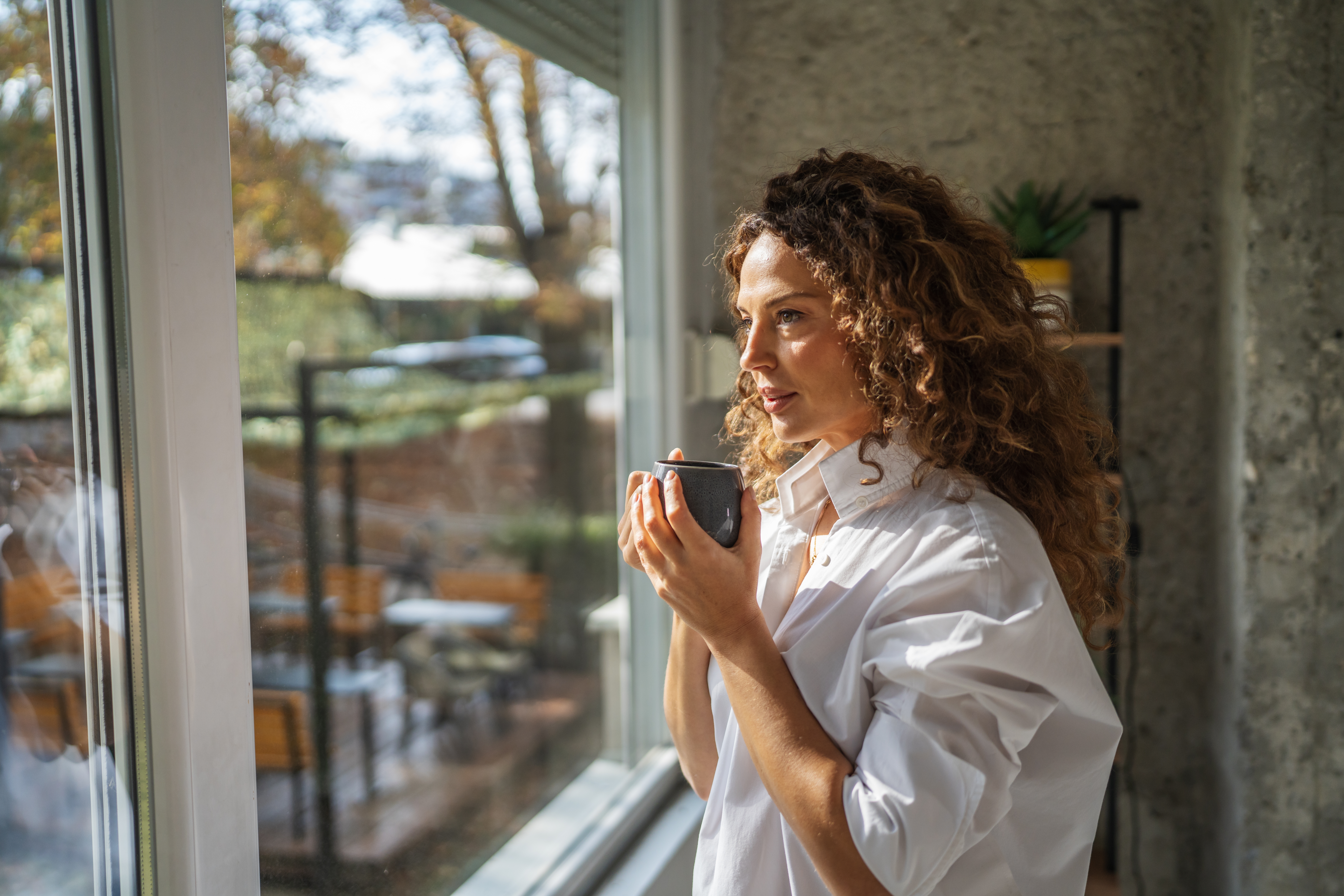 Woman,With,Curly,Brown,Hair,In,A,White,Shirt,Smiles Peaceful reflective woman outdoors